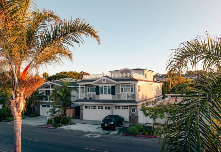 White two-story house with green trees in a residential neighborhood